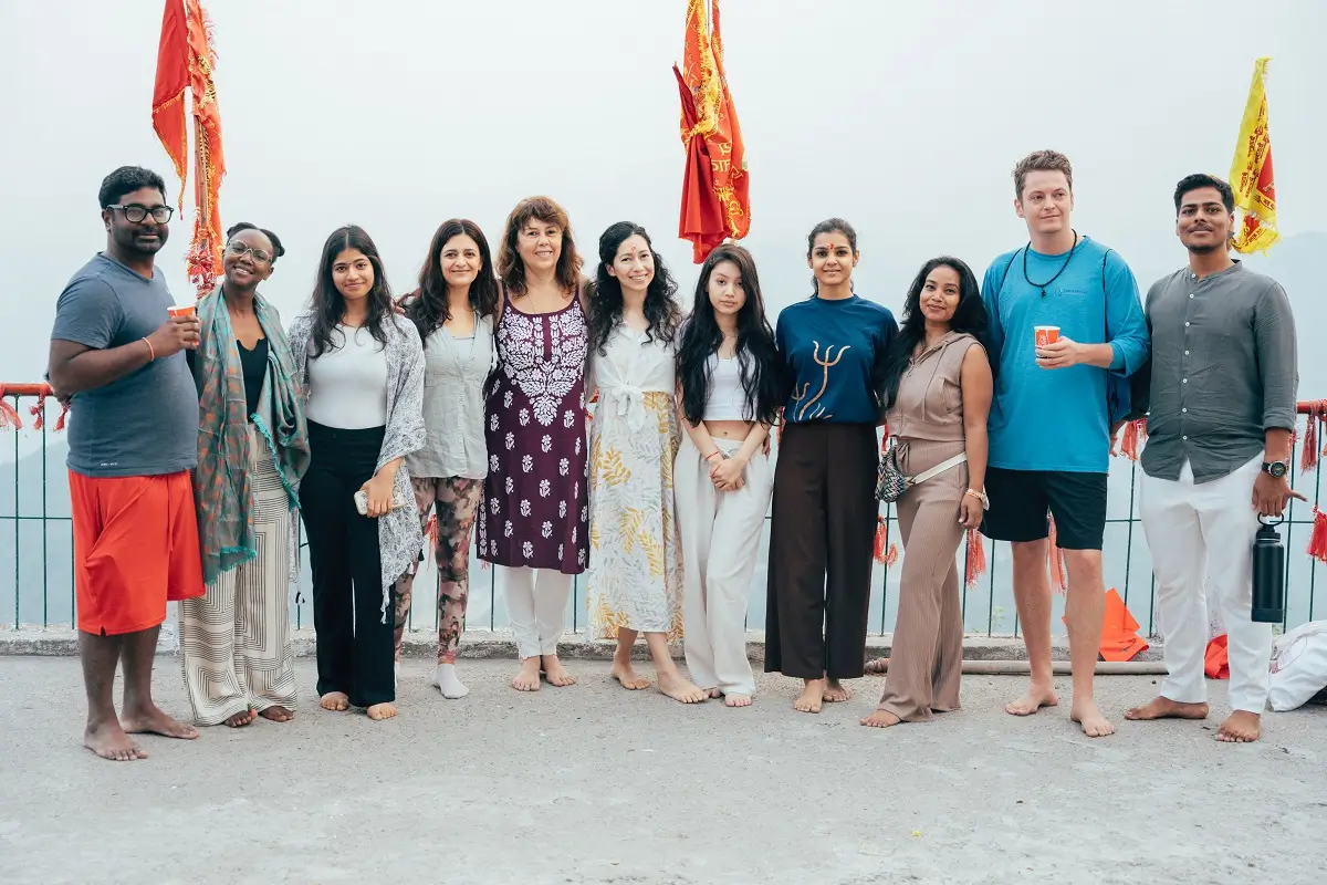 Group yoga class practising Warrior pose outdoors at a retreat in Rishikesh, India